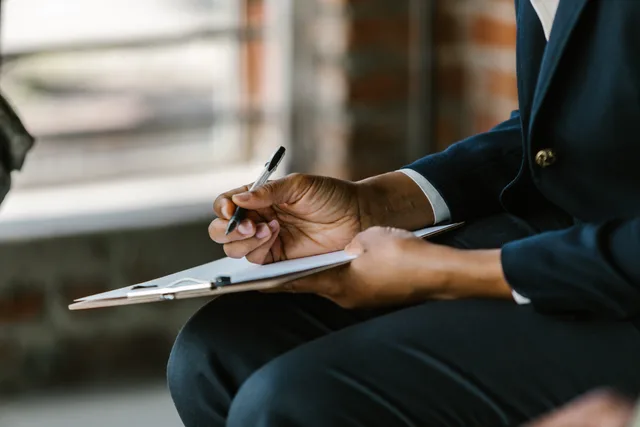 Close-up of a professional writing on clipboard indoors. Ideal for business themes. Before you sign off a sales enablement quality checklist